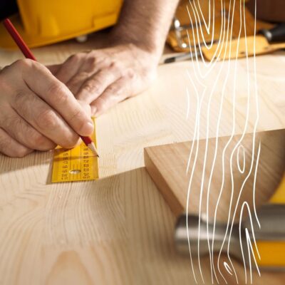 Ręka mężczyzny mierzy deskę dla projektu kuchnie na wymiar Bielska Podlaski.