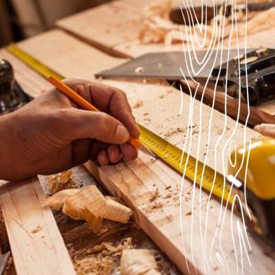 Ręka stolarza Bielsk Podlaski mierzy deskę na stole warsztatowym.