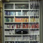 Półki z książkami w kolorach tęczy, ukazujące organizację przestrzeni w szafie przesuwnej.